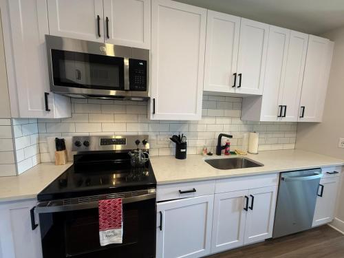a kitchen with white cabinets and a black stove top oven at Modern & Spacious Stay in Prime Location Parking in Richmond