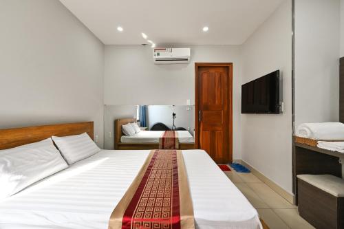 a bedroom with a large white bed and a television at Gio Hotel - near Nam Saigon International Hospital in Ho Chi Minh City