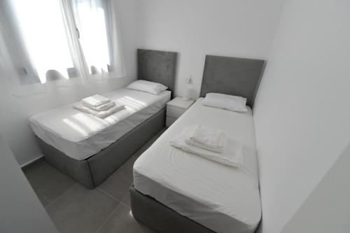 two beds in a room with white walls and windows at Oxygen Nest in Nea Kalikratia