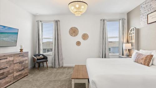 a white bedroom with a bed and a desk and windows at Upstay ChampionsGate Home w Pool BBQ & Game Room in Kissimmee