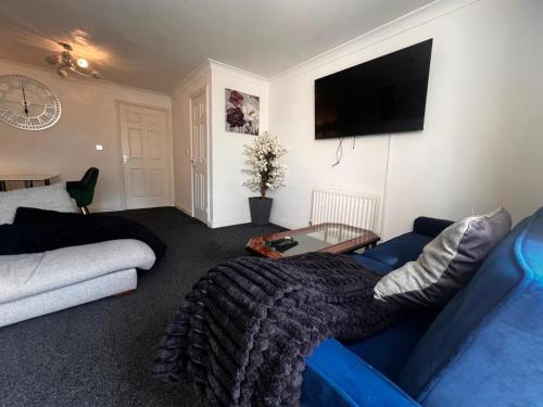 a living room with a blue couch and a flat screen tv at Exotic Maidstone Home in Maidstone