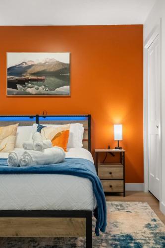 a bedroom with an orange wall and a bed at Meadowstone Suite 3BD 3 TVs Near Spruce Meadows in Calgary
