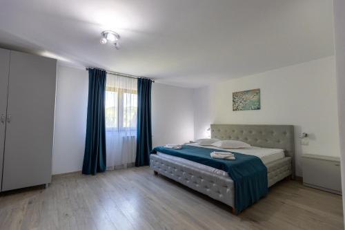 a bedroom with a bed with blue curtains at Bucovina Inn in Voronet