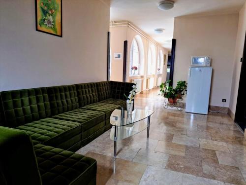 a living room with a green couch and a glass table at Parrag Panzió Mátraszentimre in Mátraszentimre