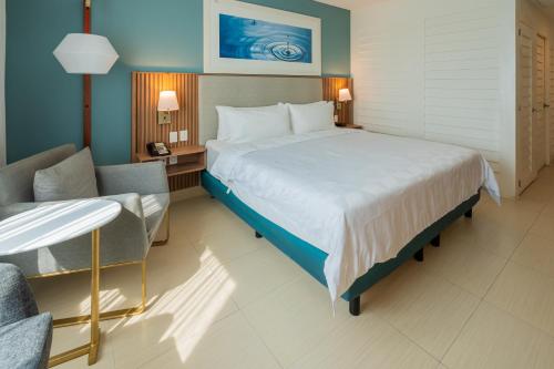 a hotel room with a large bed and a chair at Holiday Inn Acapulco La Isla by IHG in Acapulco