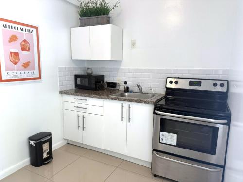 a kitchen with white cabinets and a stove at Renzzi Villas in Miami