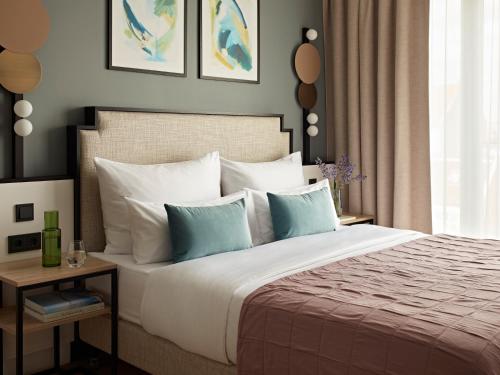 a bedroom with a large bed with white and blue pillows at Numa Berlin Arc in Berlin