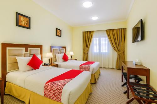 a hotel room with two beds and a desk at Ruwi Hotel Apartments, Sharjah in Sharjah