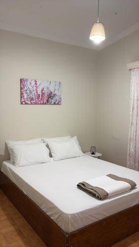 a bed with white sheets and a picture on the wall at HeidiHouse in Patra