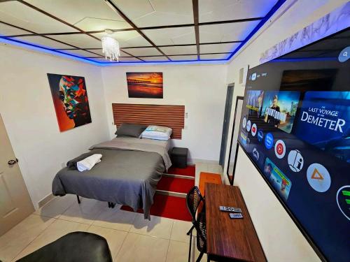 a bedroom with a bed and a large screen at Sunrise Haven Holiday Apartments Barbados in Christ Church
