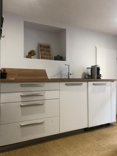 une cuisine avec des armoires blanches et un comptoir dans l'établissement Baccarat - Cristal Appartement - 25m2, à Baccarat