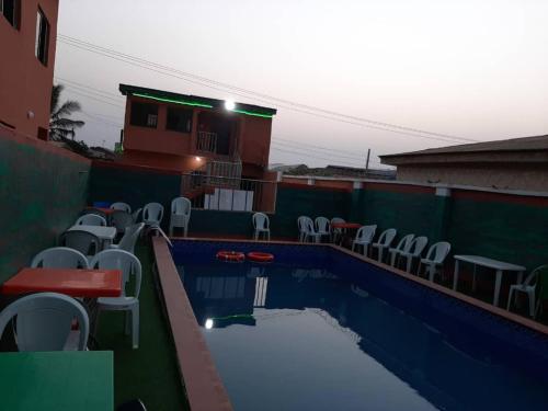 a swimming pool with chairs and tables and a building at Pasasa Hotel & Event Centre in Lafenwa