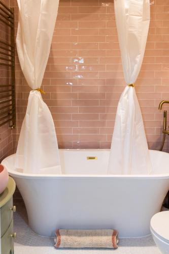 a white bath tub with curtains in a bathroom at Mill Cottage in Newlands