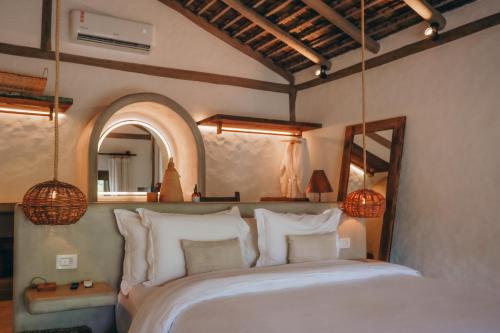 a bedroom with a large white bed with a mirror at Anacardier Privé Hotel in Atins