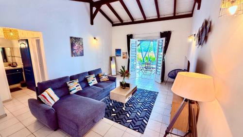a living room with a blue couch and a table at Géko, piscine, jardin, paisible in Sainte-Luce
