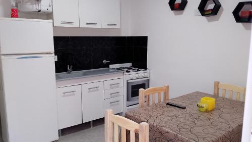 a small kitchen with a table and a refrigerator at Departamento NAMASTE II in Carhué