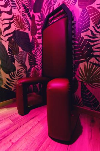 a black chair in a room with a pink wall at Love room L'écrin tropical in Aubers