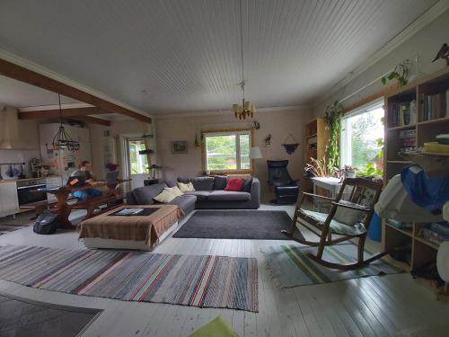 a living room with a couch and a man playing a guitar at Rooms in a big wooden home, kotimajoitus, homestay in Muonio