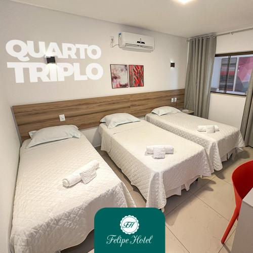 a hotel room with three beds and a sign on the wall at Felipe Hotel in Serra Talhada