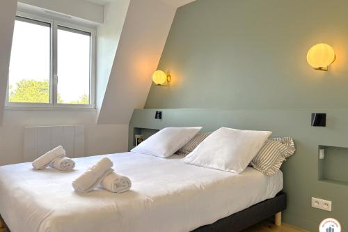 Un dormitorio con una gran cama blanca con toallas. en Le Palais des Terrasses, en Tourgéville