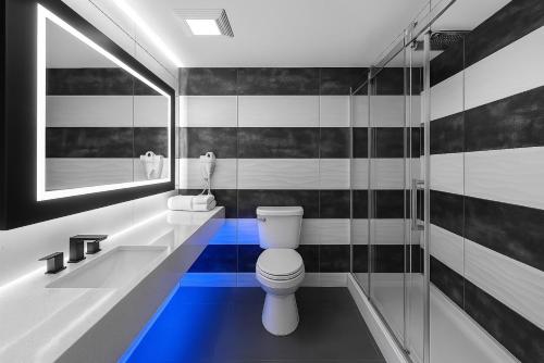 a bathroom with a toilet and a sink and a mirror at Casa Azul Hotel Blu-UBS Arena in Queens