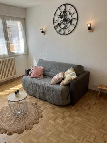 un salon avec un canapé et une horloge au mur dans l'établissement Studio Aix les Bains entre centre-ville et lac, à Aix-les-Bains