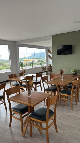 a restaurant with wooden tables and chairs and windows at Hotel Dois Montes in Itamaraju