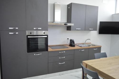 una cucina con armadi grigi e tavolo in legno di La perla di Giada 1 a Bisceglie