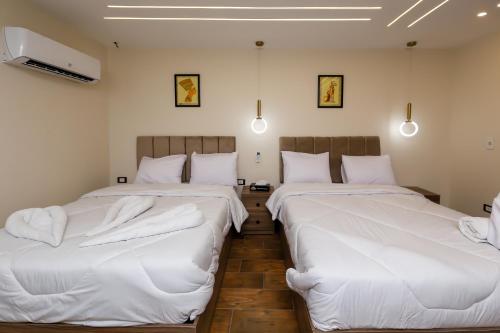 two beds in a room with white sheets at Rotana Pyramids View in Cairo