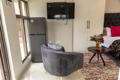 a living room with a chair and a bed at Casa Amora! in Mpemba