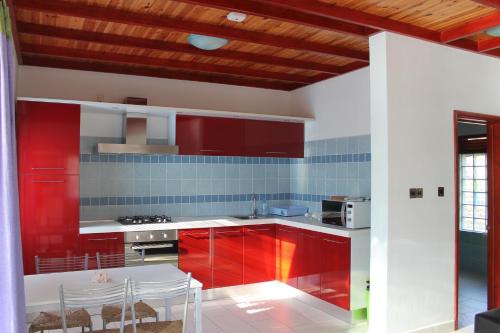 cocina con armarios rojos, mesa y sillas en Green Blue Beach House, en Baie Lazare Mahé