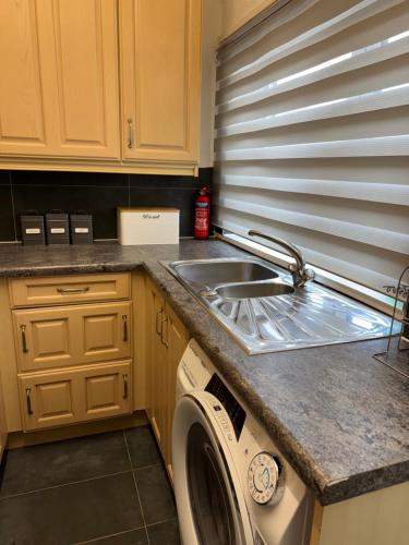 a kitchen with a sink and a washing machine at Brits-Halley Luxury Apartments in Annfield Plain