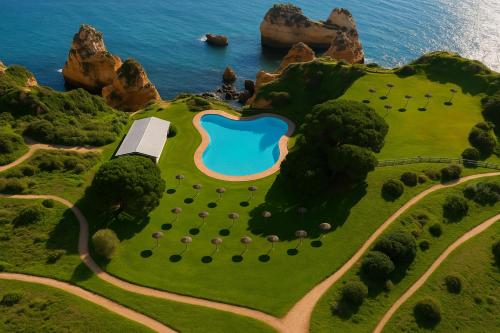 an island with a swimming pool on a hill next to the ocean at Prainha Residences-A17 -Portimão in Alvor