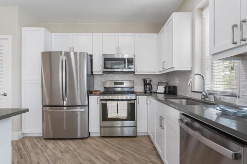 a kitchen with white cabinets and a stainless steel refrigerator at Multiple Hollywood Apartments Hub in Los Angeles