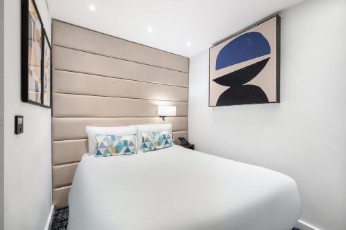 a bedroom with a white bed and a headboard at voco London Marylebone by IHG in London