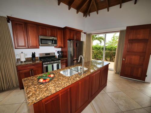 a kitchen with wooden cabinets and a counter top with a sink at Spectacular Luxury Rental With Ocean Views And Private Pool in Roatan