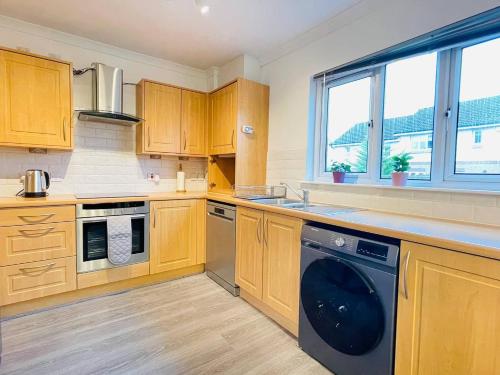 a kitchen with wooden cabinets and a dishwasher at Elegant 3BR house in Glasgow in Garthamlock