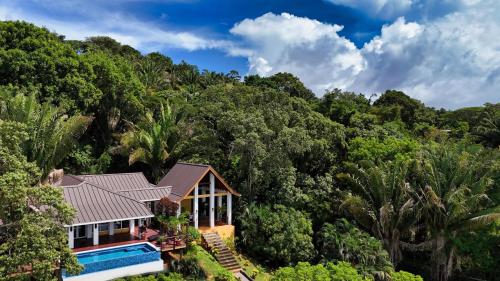 an aerial view of a house in the forest at Relax At This Hillside Retreat That Overlooks The Lush Forest And The Caribbean, in West End