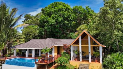 a house with a swimming pool in front of it at Relax At This Hillside Retreat That Overlooks The Lush Forest And The Caribbean, in West End