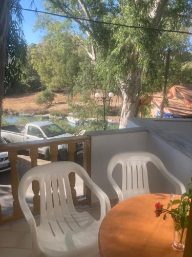 two white chairs and a wooden table on a balcony at Liberty-Room N2 in Georgioupolis