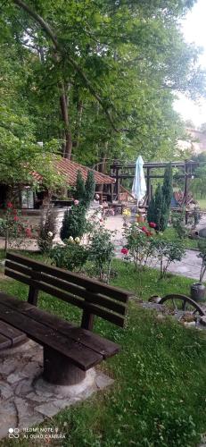 a park with a wooden bench in the grass at Парк - Хотел Макензен in Melnik