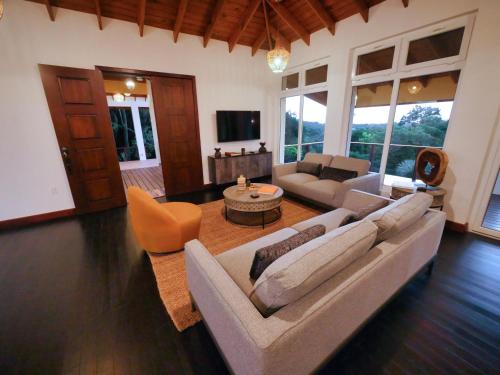 a living room with a couch and a table at Relax At This Hillside Retreat That Overlooks The Lush Forest And The Caribbean, in West End