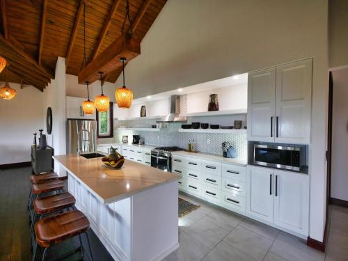 a large kitchen with white cabinets and a large island at Relax At This Hillside Retreat That Overlooks The Lush Forest And The Caribbean, in West End