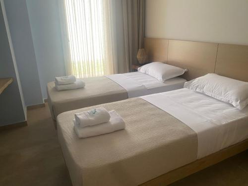 two beds in a hotel room with towels on them at Vila Palasea in Palasë