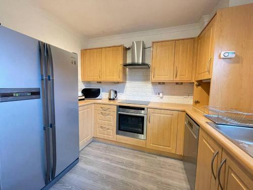 a kitchen with wooden cabinets and a stainless steel refrigerator at Elegant 3BR house in Glasgow in Garthamlock