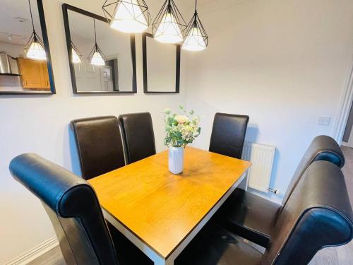 a dining room with a wooden table and leather chairs at Elegant 3BR house in Glasgow in Garthamlock
