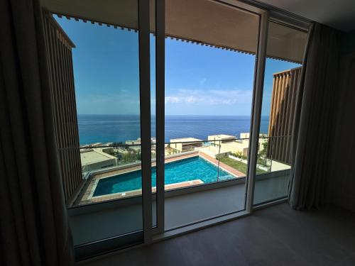 a window with a view of a swimming pool and the ocean at Vila Palasea in Palasë