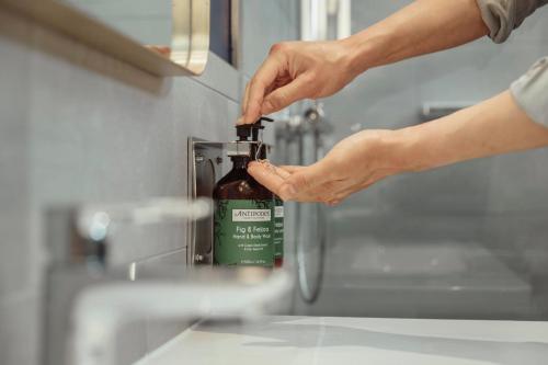 a person holding a bottle of alcohol in a sink at voco London Marylebone by IHG in London