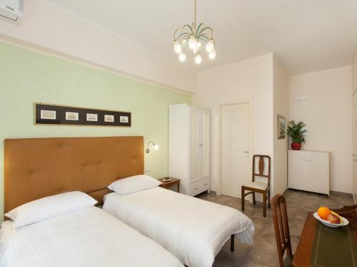 a bedroom with two beds and a table and a chair at Anice Affittacamere in Rome