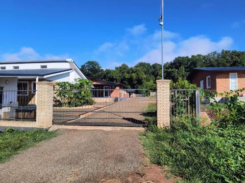 a fence in front of a house with a gate at Casa Shalom 2 Room App! Internet! Parking! Sauna! Quiet! Central! Esperanza village! in Hohenau